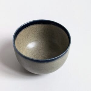 Petite tasse artisanale en porcelaine, émail céladon, rehaussée d'un émail noir sur la lèvre.